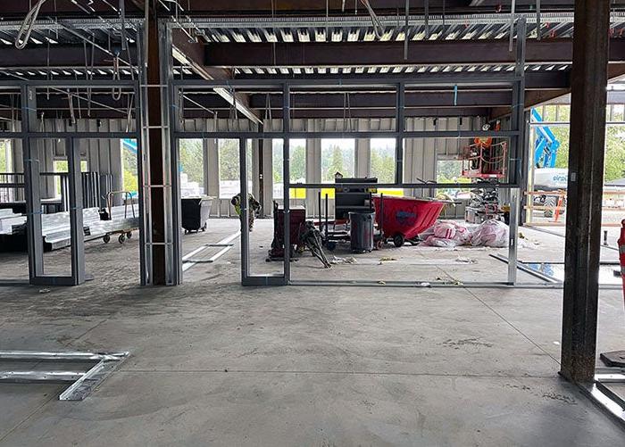 inside a partially built building with steel framing for walls being installed on a concrete floor