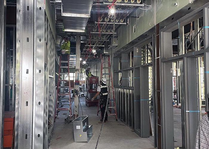 inside a partially constructed hallway with metal studs and people working