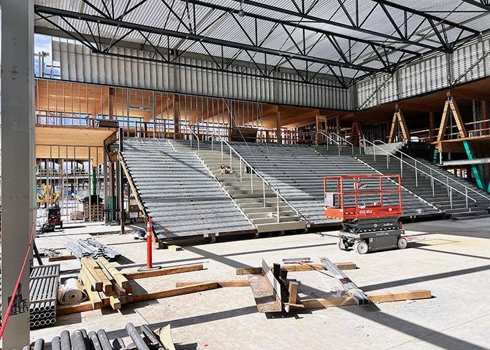 large interior room under construction with framing on one side for stairs. there is materials and equipment in the space.