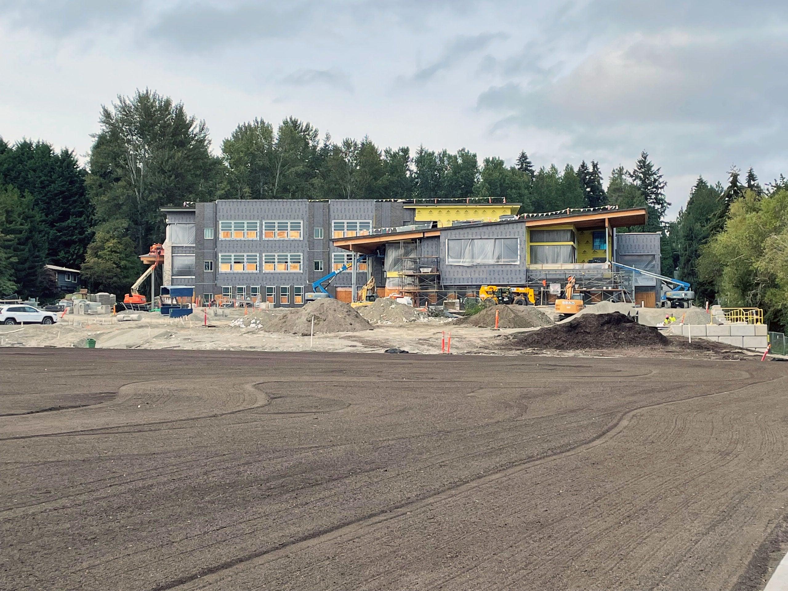 a large building under construction with a field of soil in front